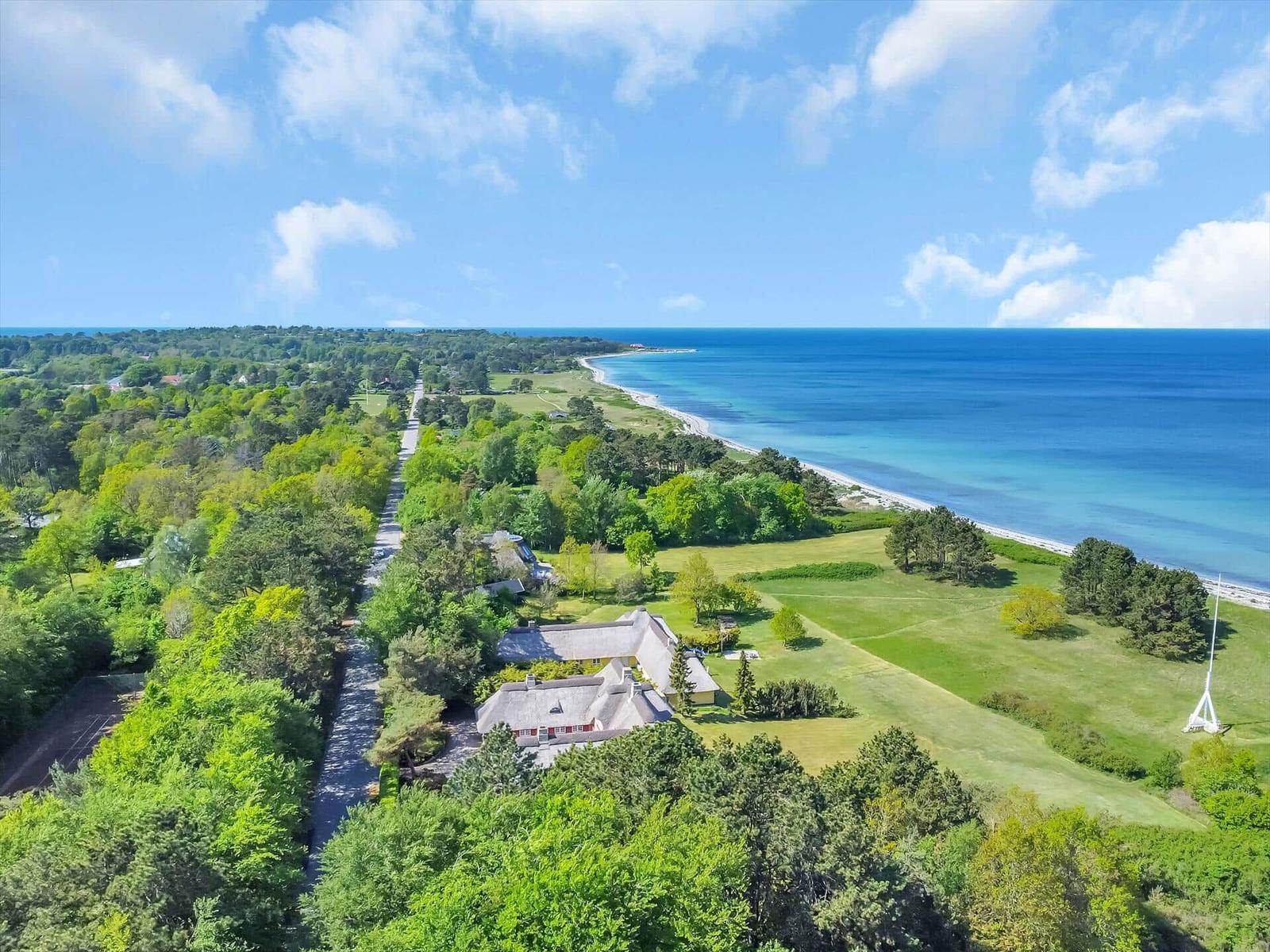 Haus mit Garten, Wald und Strand im Hintergrund