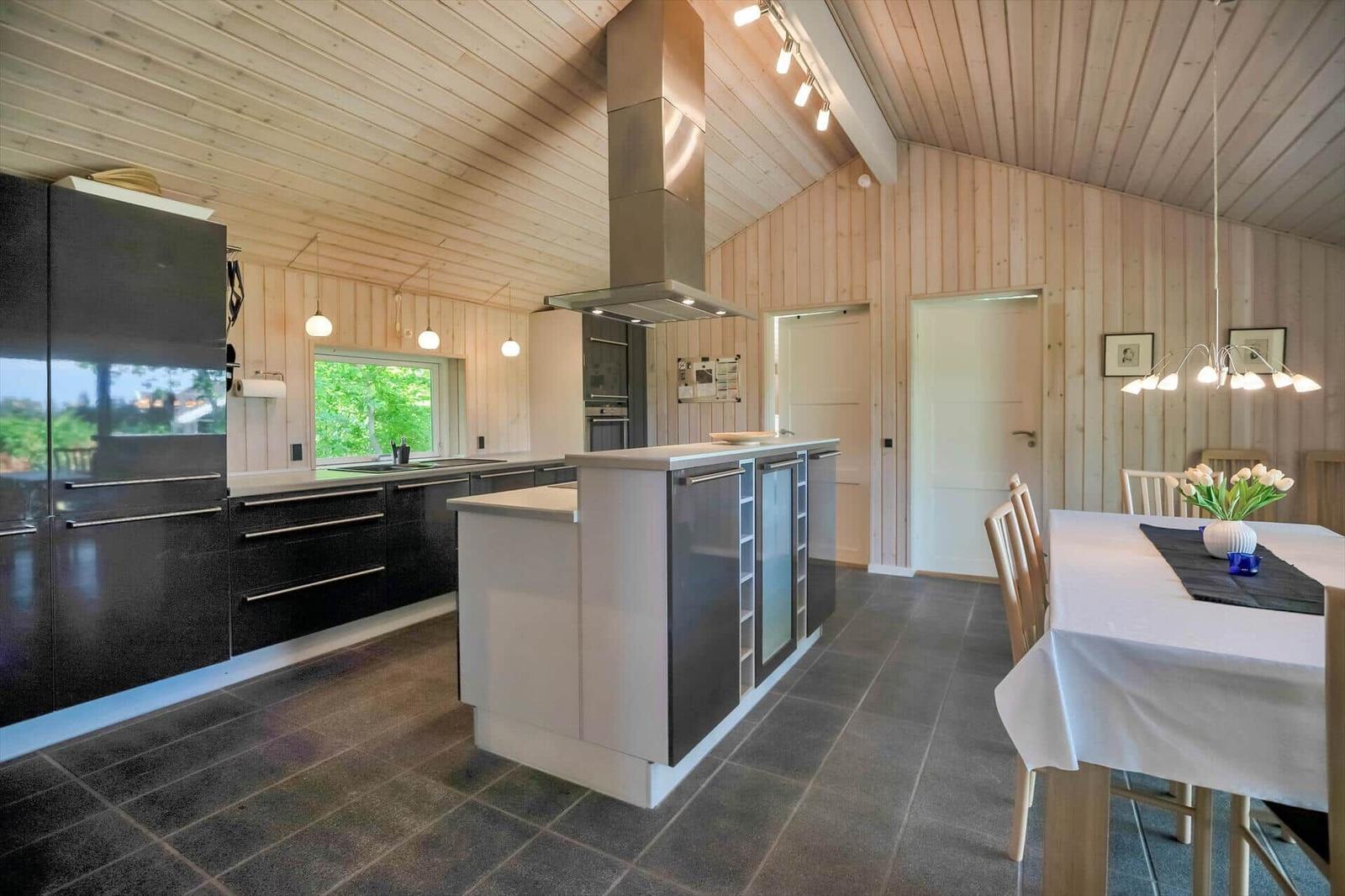 Moderne Küche mit Kücheninsel und Essbereich. Holzwände und -decke.