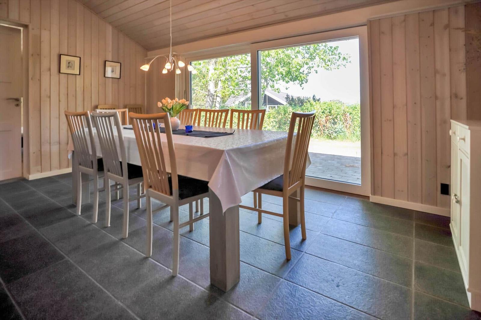 Esszimmer mit Holzwand, Tisch mit Stühlen und Blick auf Garten