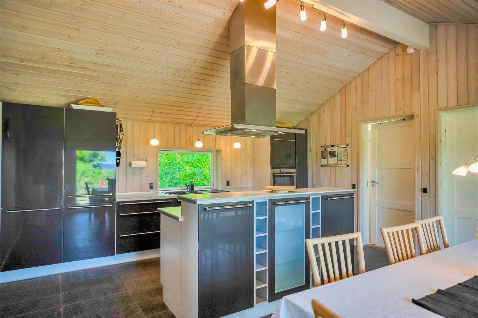 Moderne Küche mit Holzwand und -decke, Kücheninsel und Essbereich.