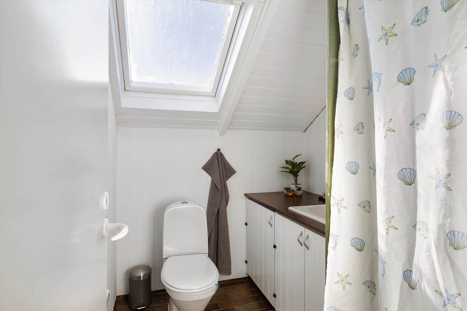 Badezimmer mit Toilette, Waschbecken und Dusche mit Meerestier-Muster.