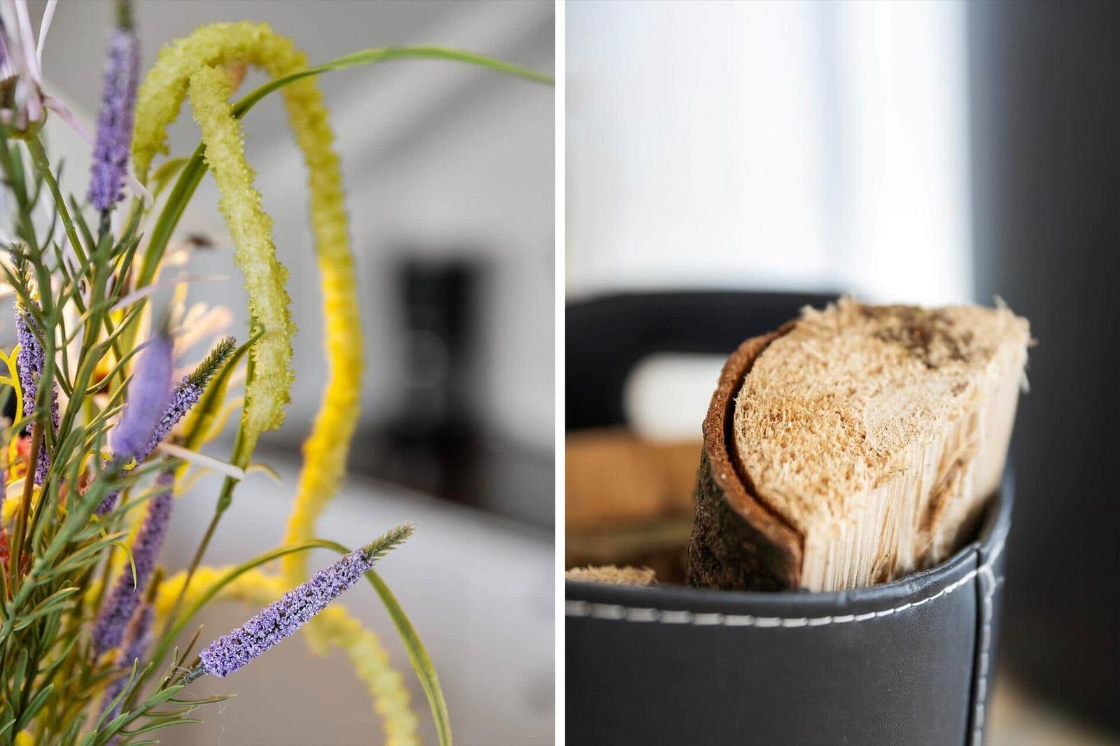 Blumenstrauß mit lila und gelben Blüten. Holzscheite in einem schwarzen Korb.
