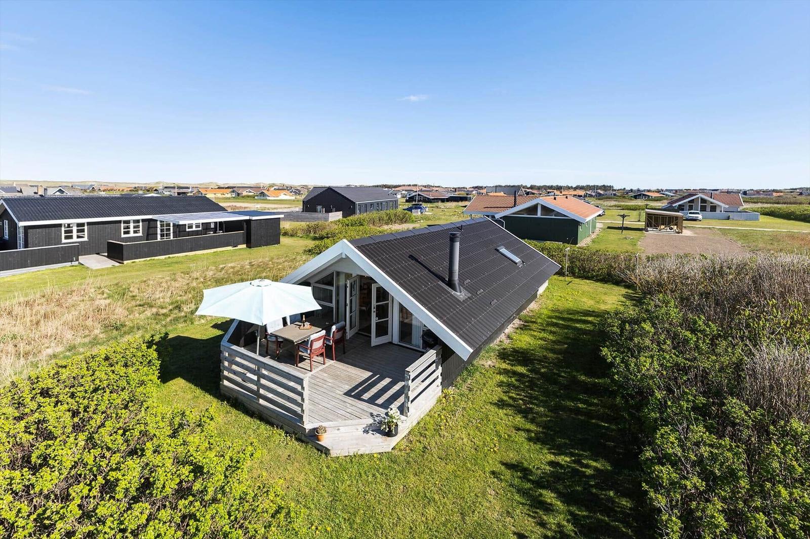 Haus mit Terrasse und Sonnenschirm in grüner Umgebung