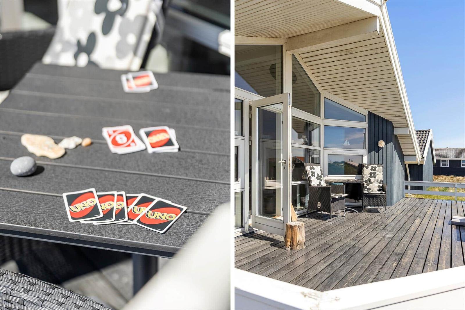 Terrasse mit Sitzgelegenheiten und UNO-Karten. Modernes Haus mit Glasfront und Holzdecke.
