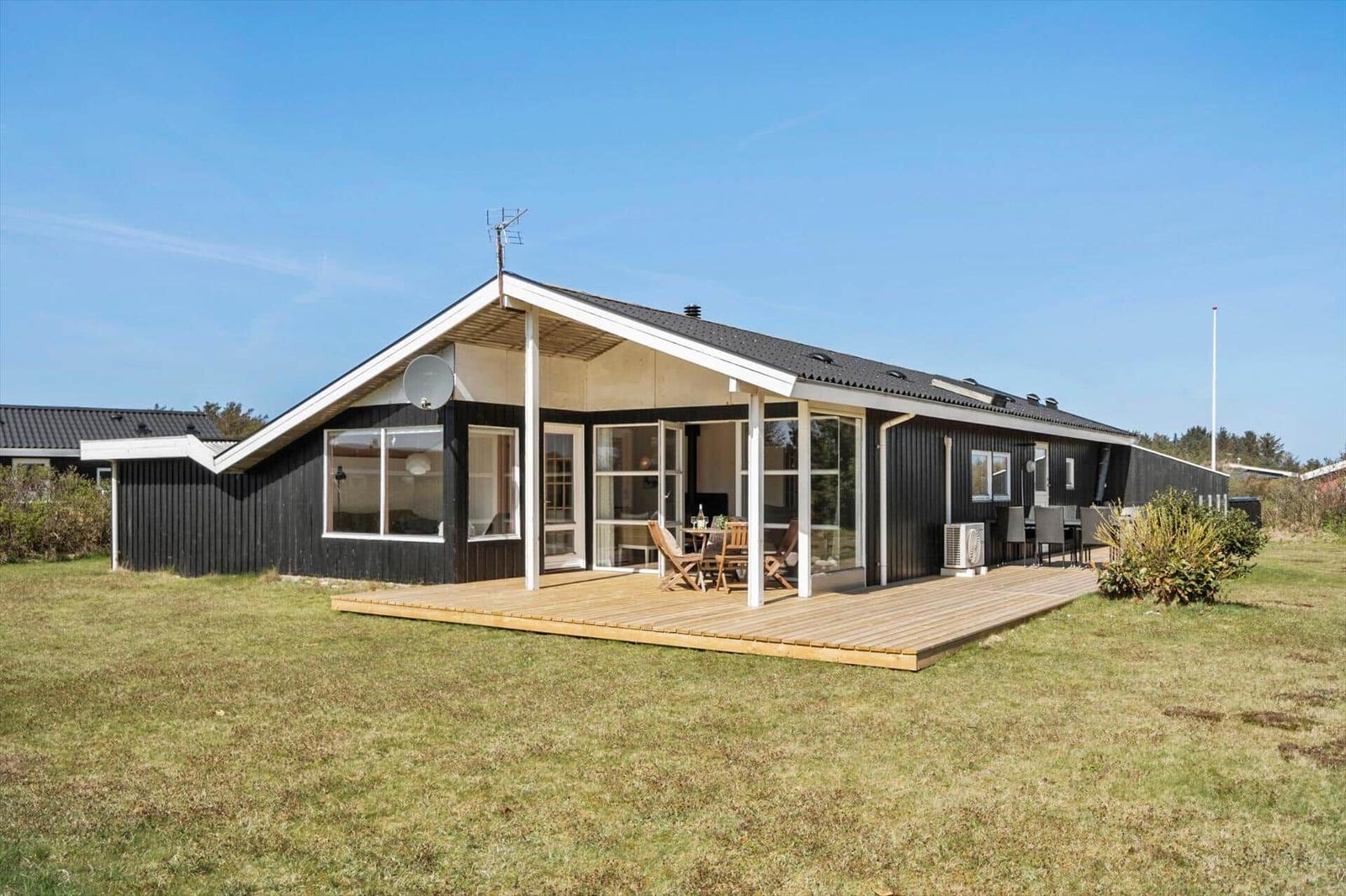 Ein modernes Haus mit Holzterrasse und großzügigen Fenstern.