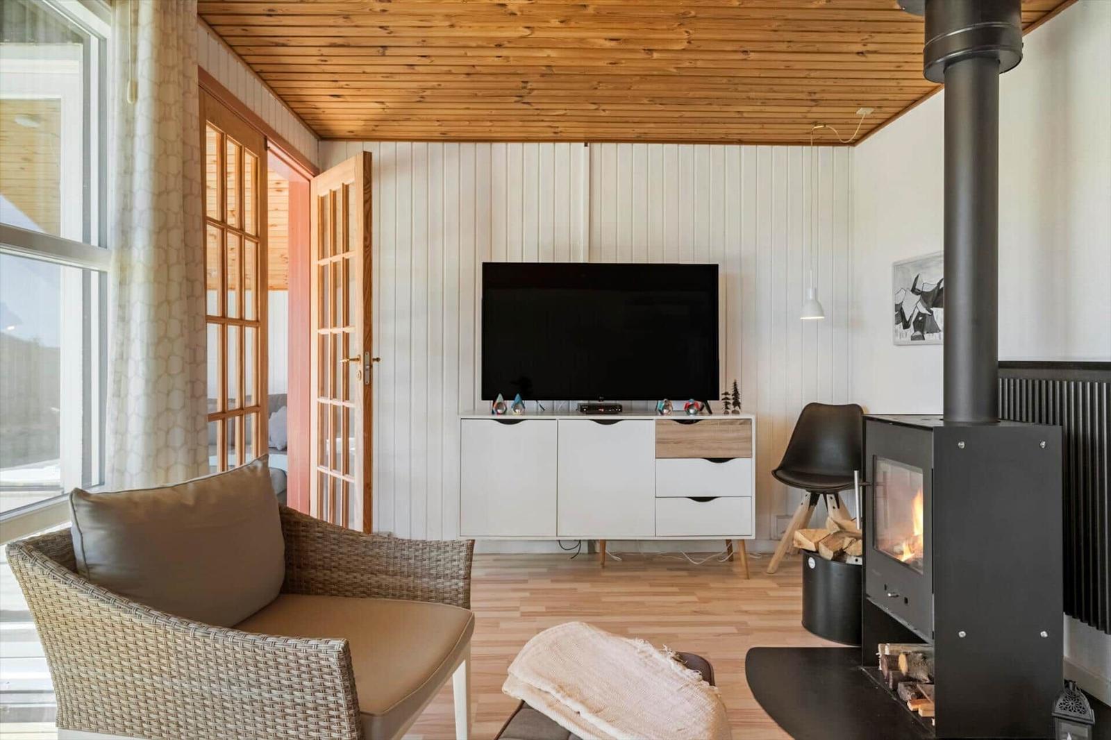 Wohnzimmer mit Kamin, Fernseher und Sitzgelegenheit.