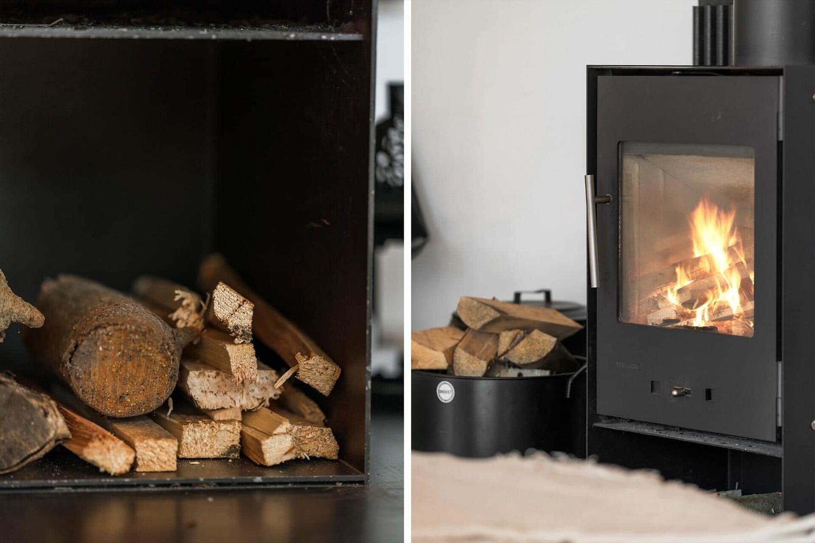 Holzstapel neben einem brennenden Kaminofen mit sichtbarem Feuer.