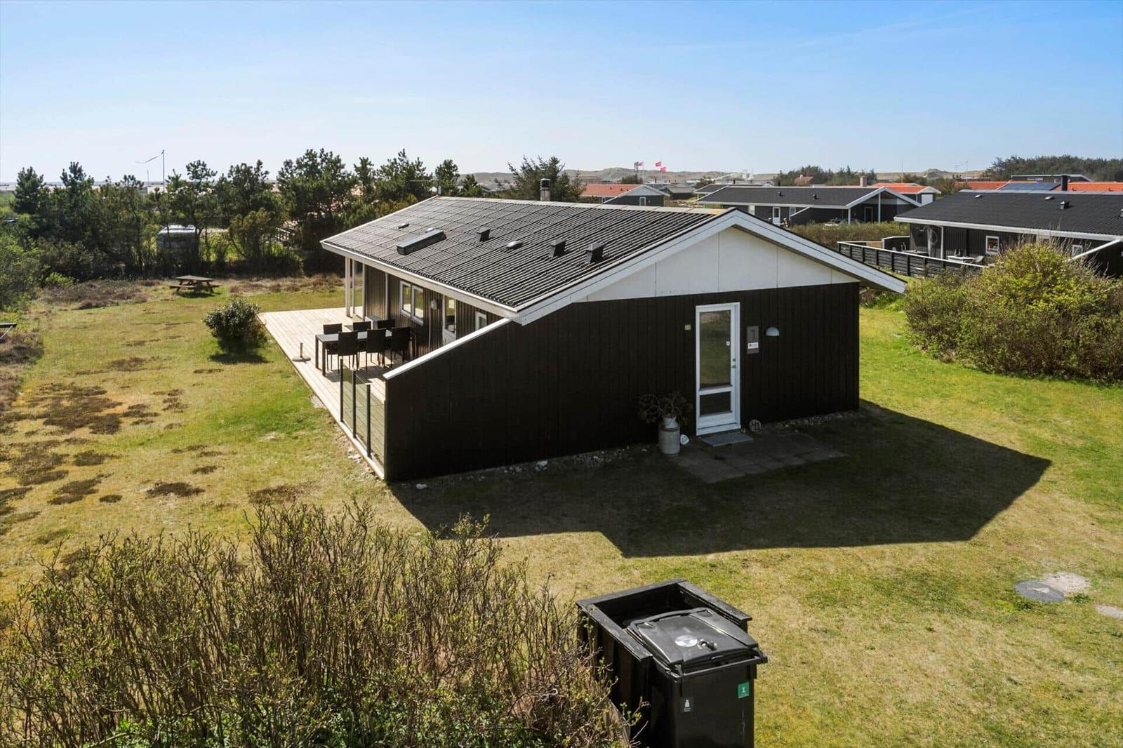 Ein modernes Haus mit Terrasse und Garten. Umgeben von Grünflächen und Bäumen.