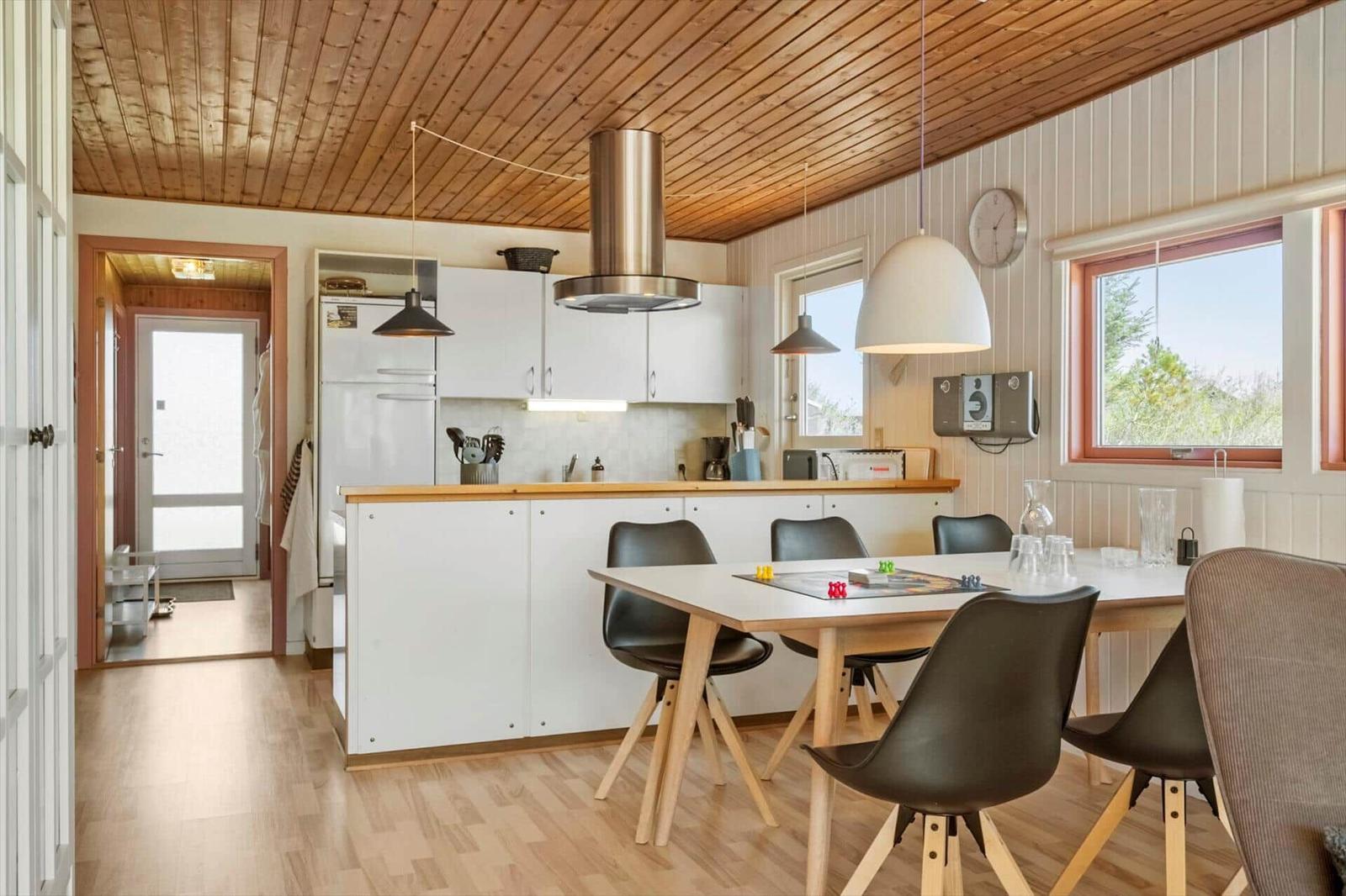 Küche mit Essbereich, Holzdecke und Fenster zum Blick ins Freie.