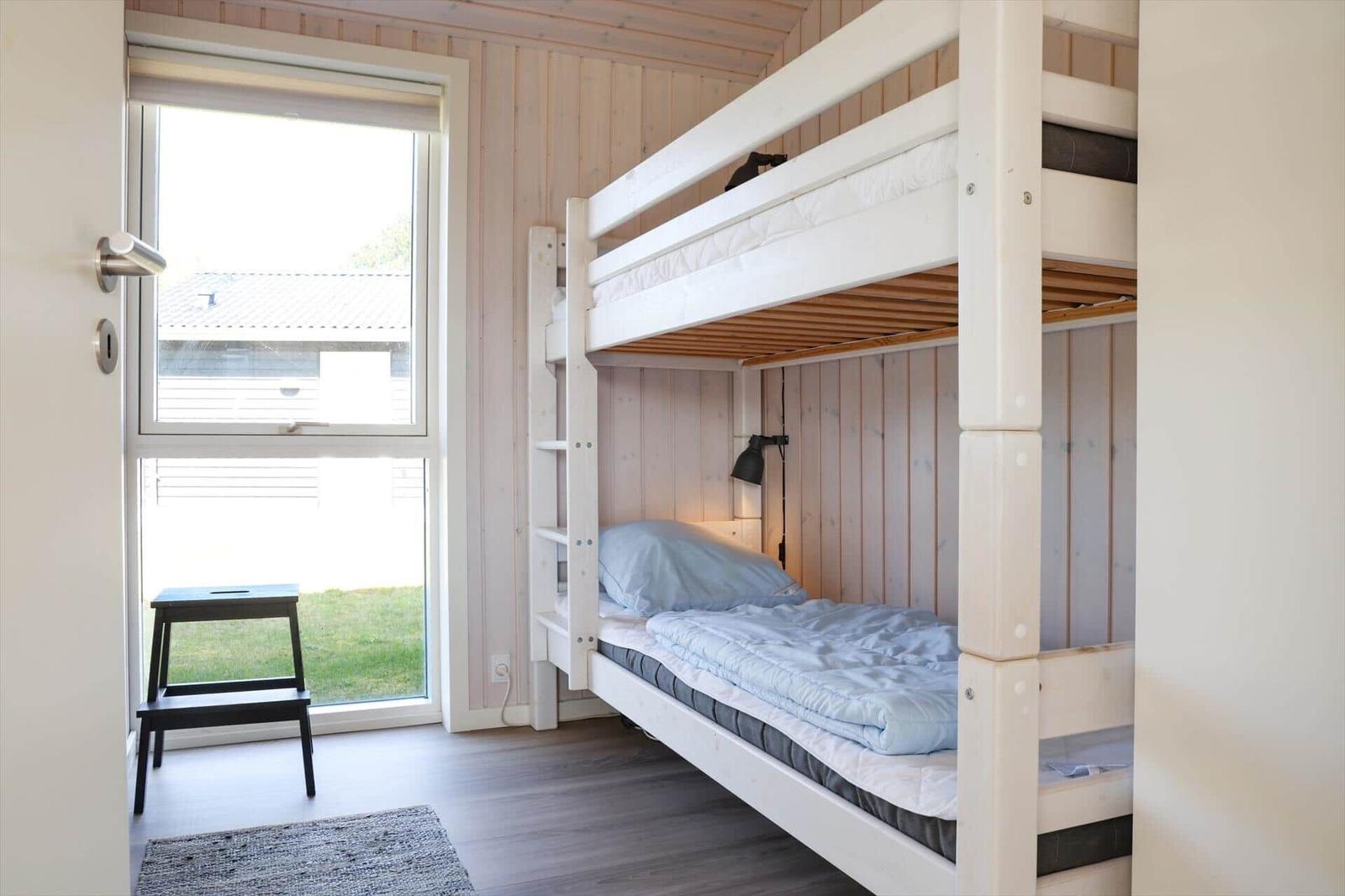 Zimmer mit Doppelstockbett, Fenster und Stuhl.