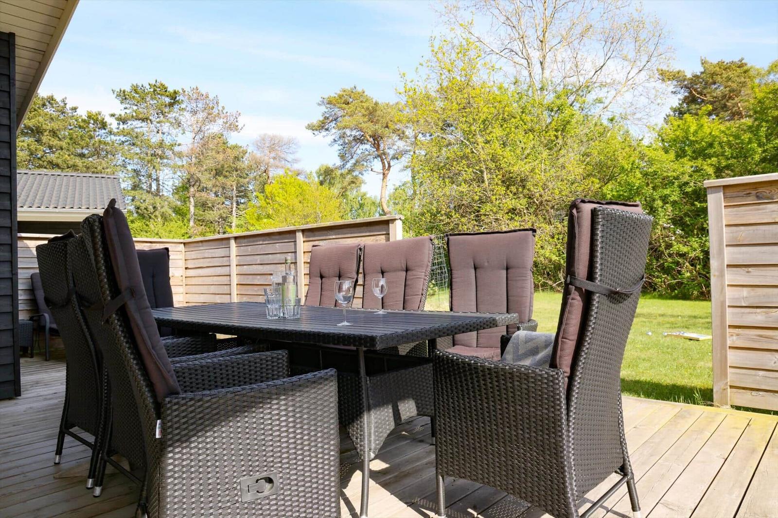 Terrasse mit Sitzgruppe und Tisch. Hintergrund: Wald und Holzzaun.