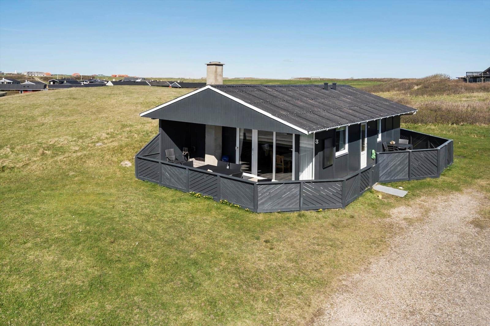 Ein schlichtes Ferienhaus mit Balkon und Grillplatz in einer grünen Landschaft.