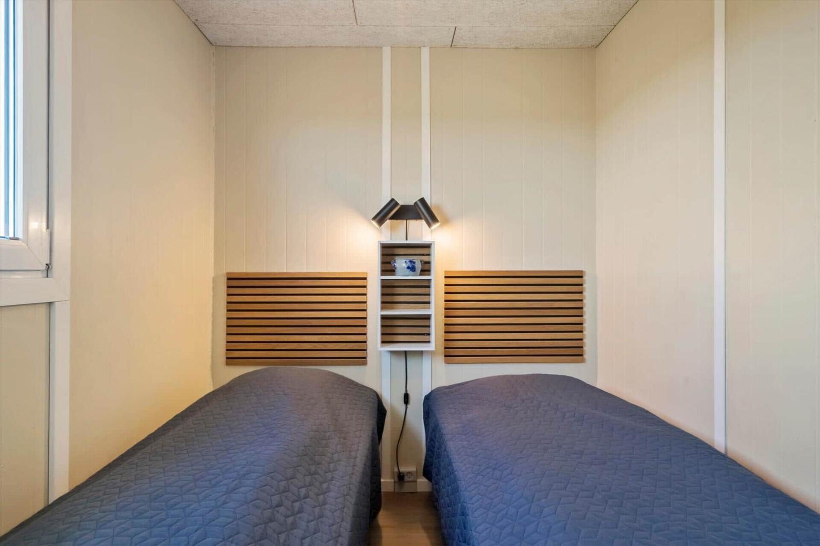 Zwei Betten mit Holz-Kopfteil und Wandlampe