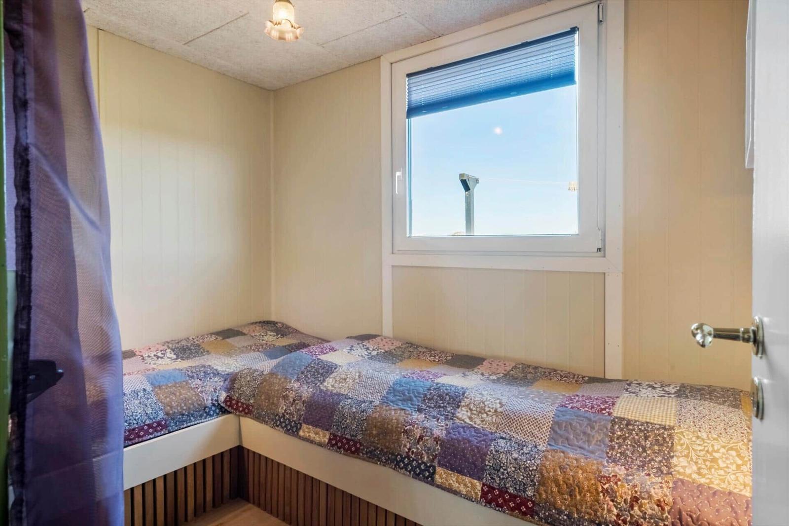 Schlafzimmer mit Eckschlafcouch, Fenster und Deckenleuchte.