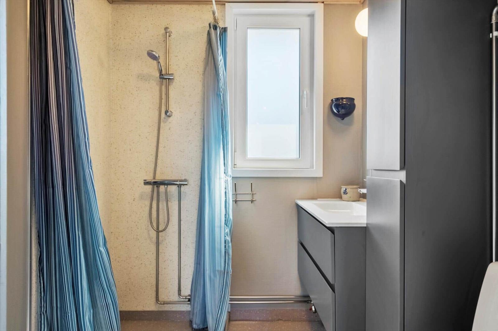 Bad mit Dusche, Fenster und Waschbecken