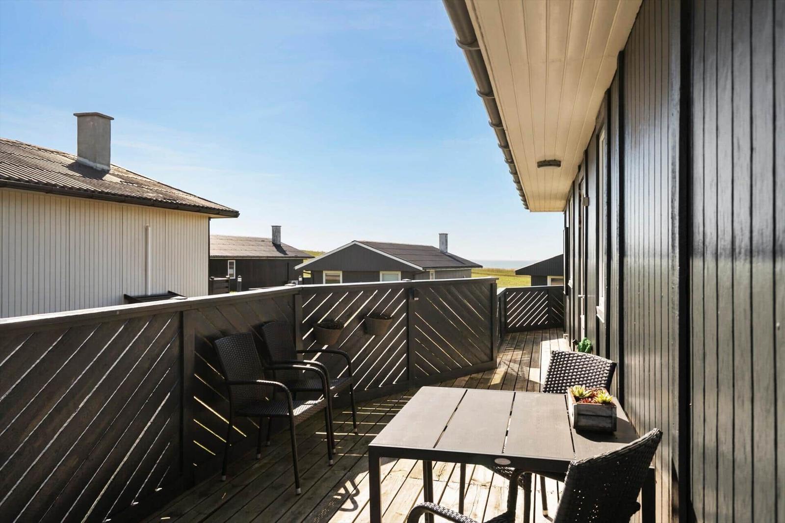 Terrasse mit Tisch und Stühlen, Blick auf andere Häuser und Horizont.