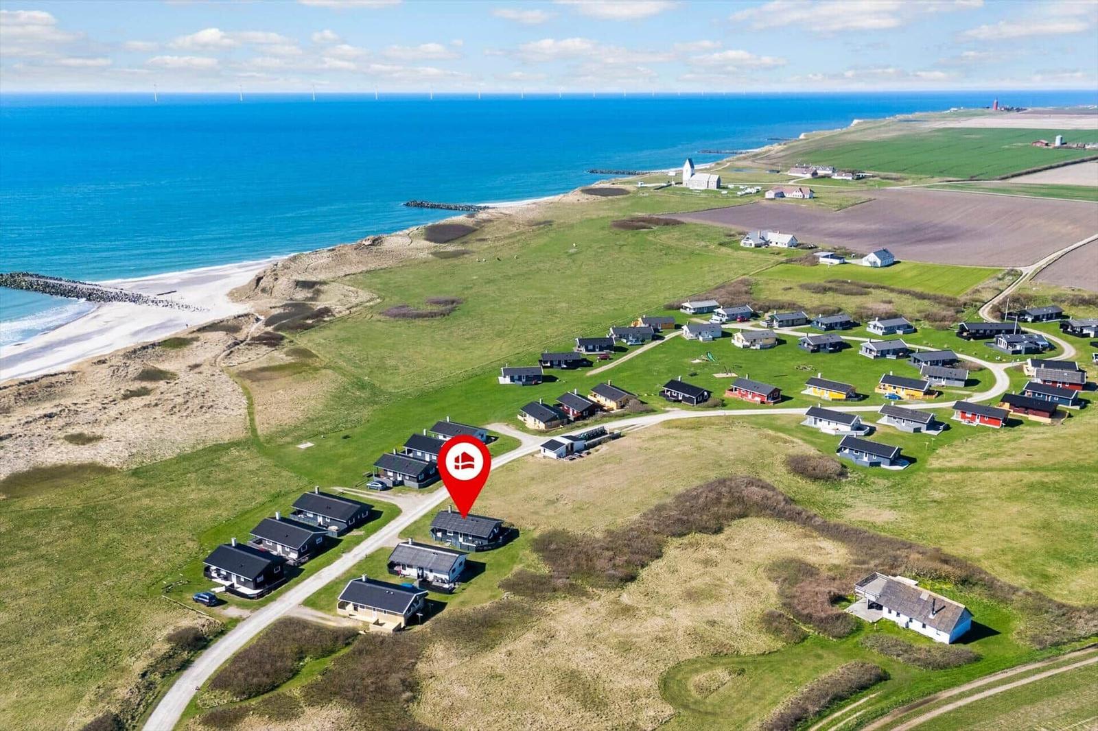 Urlaubshotel an der Küste mit Blick auf das Meer und Windkraftanlagen.