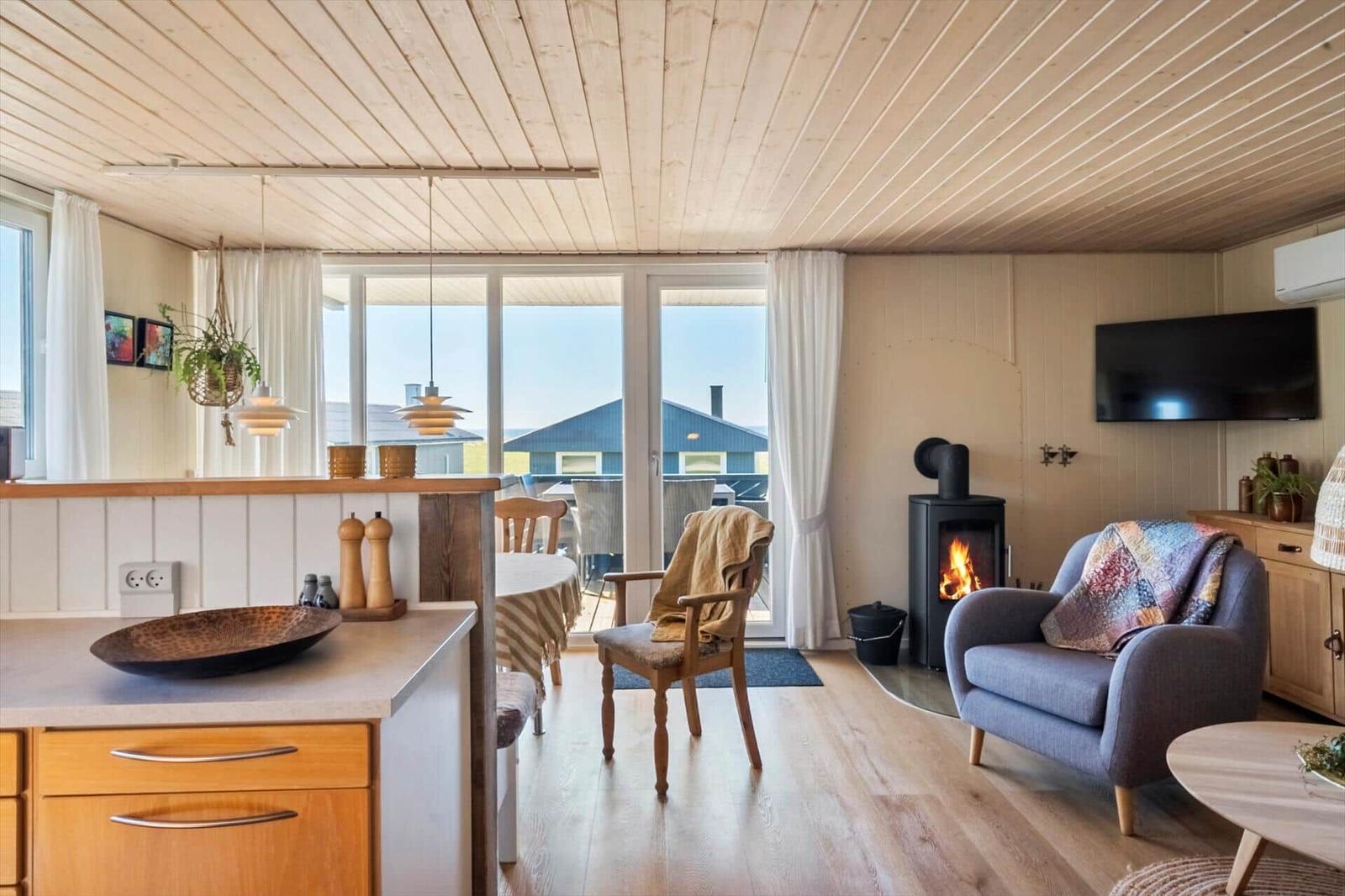 Wohnbereich mit Kamin, Sitzgelegenheiten und Blick auf Balkon.