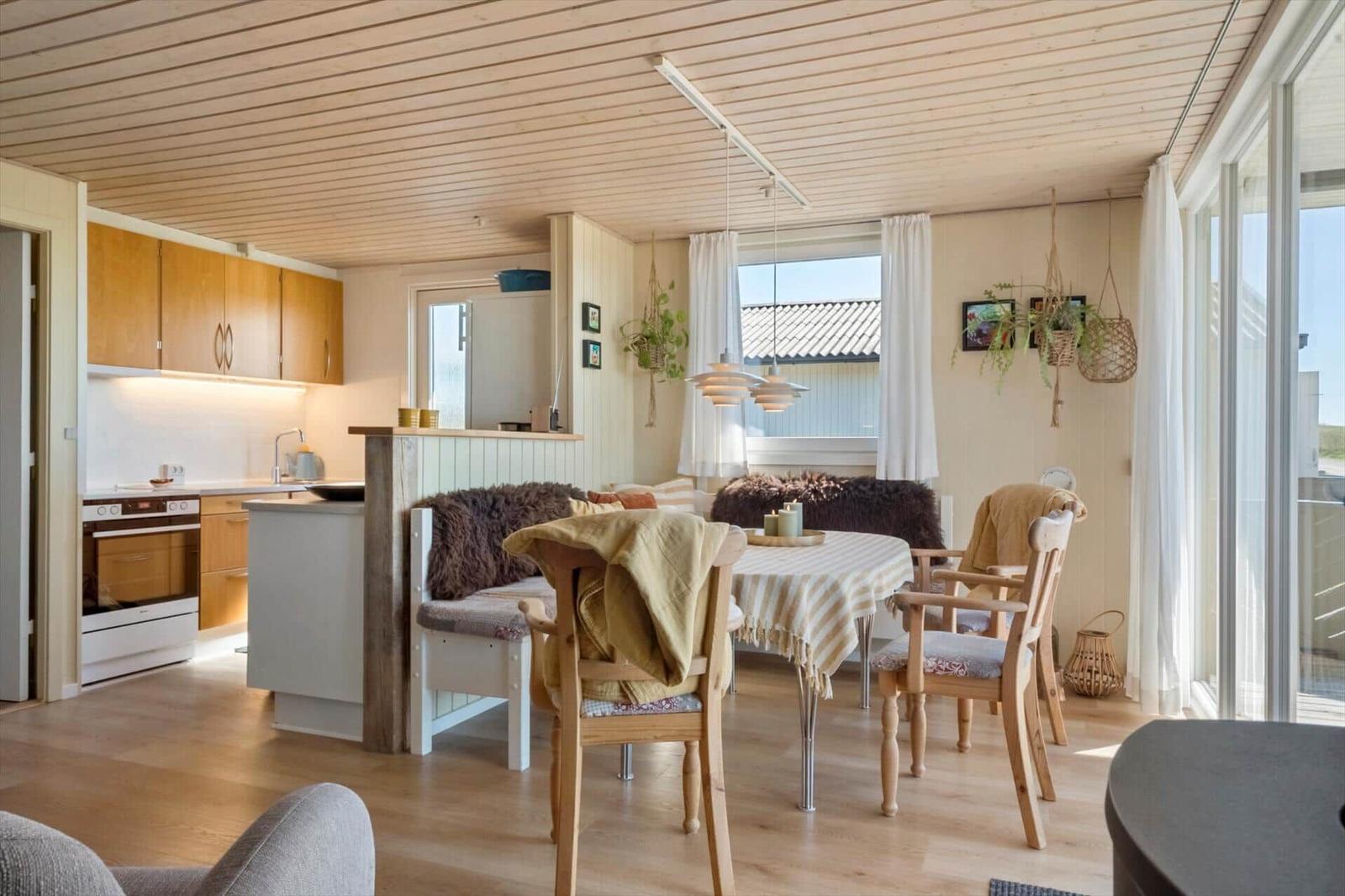 Küche und Essbereich mit Holzmöbeln und Fenstern. Tisch mit Tischdecke und Stühle.