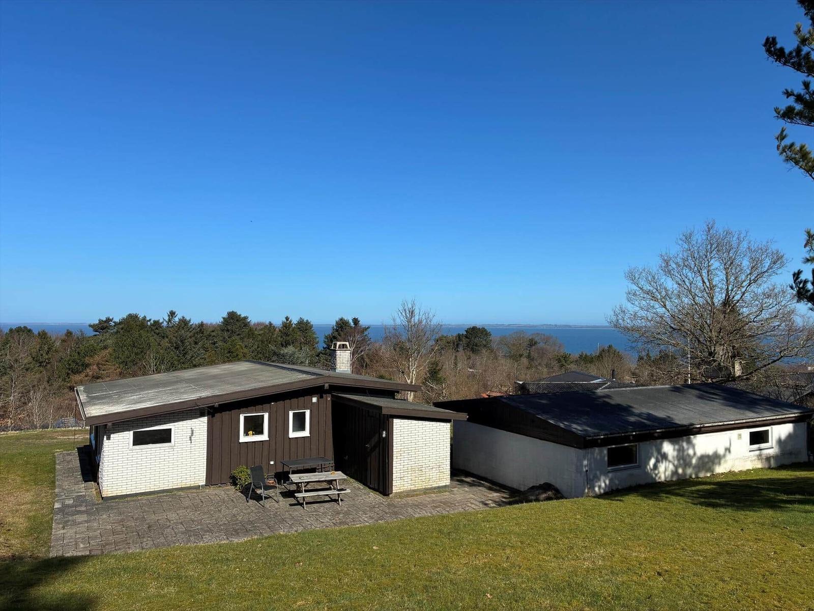 House with terrace and sea view. Lawn and trees surround the accommodation.