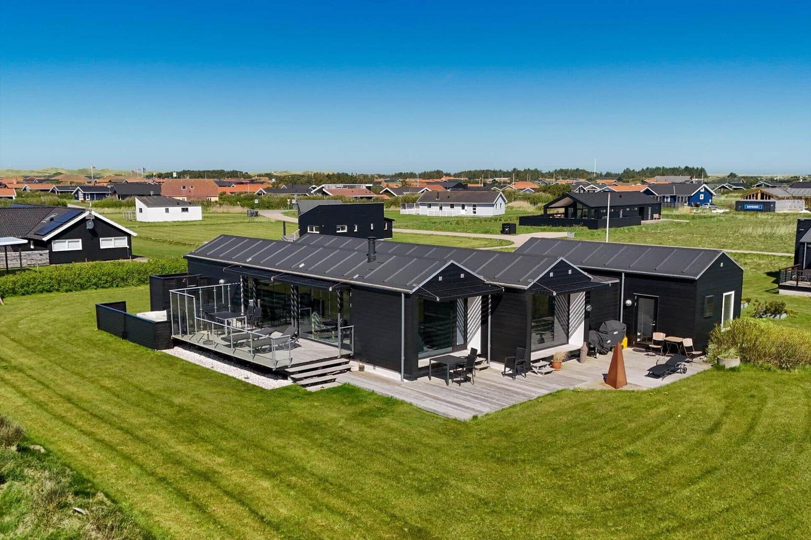 Moderne schwarze Ferienhaus mit großem Garten und Terrasse. Blick auf die Umgebung.