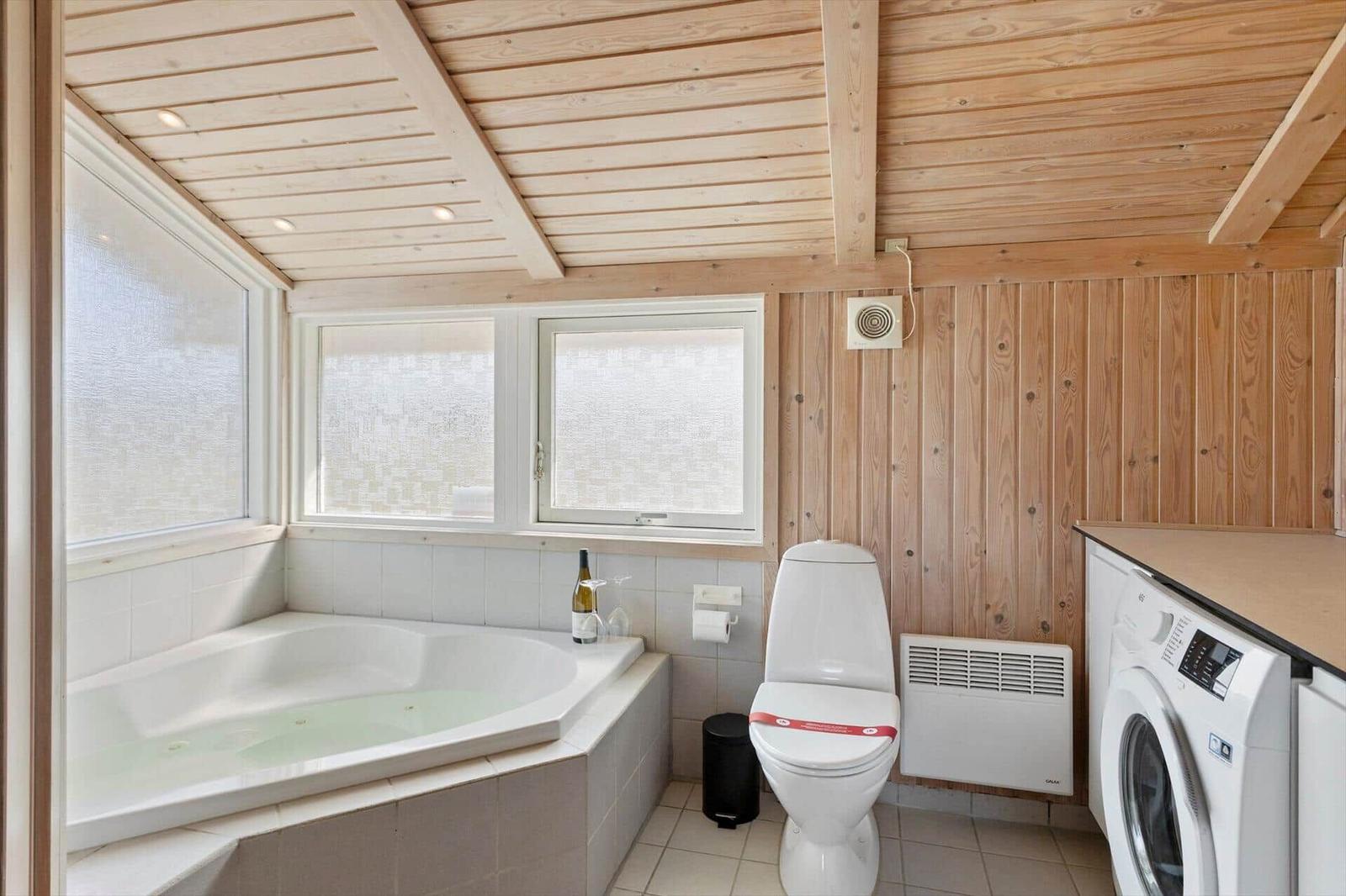 Bad mit Whirlpool, Toilette und Waschmaschine. Holzwand und -decke.