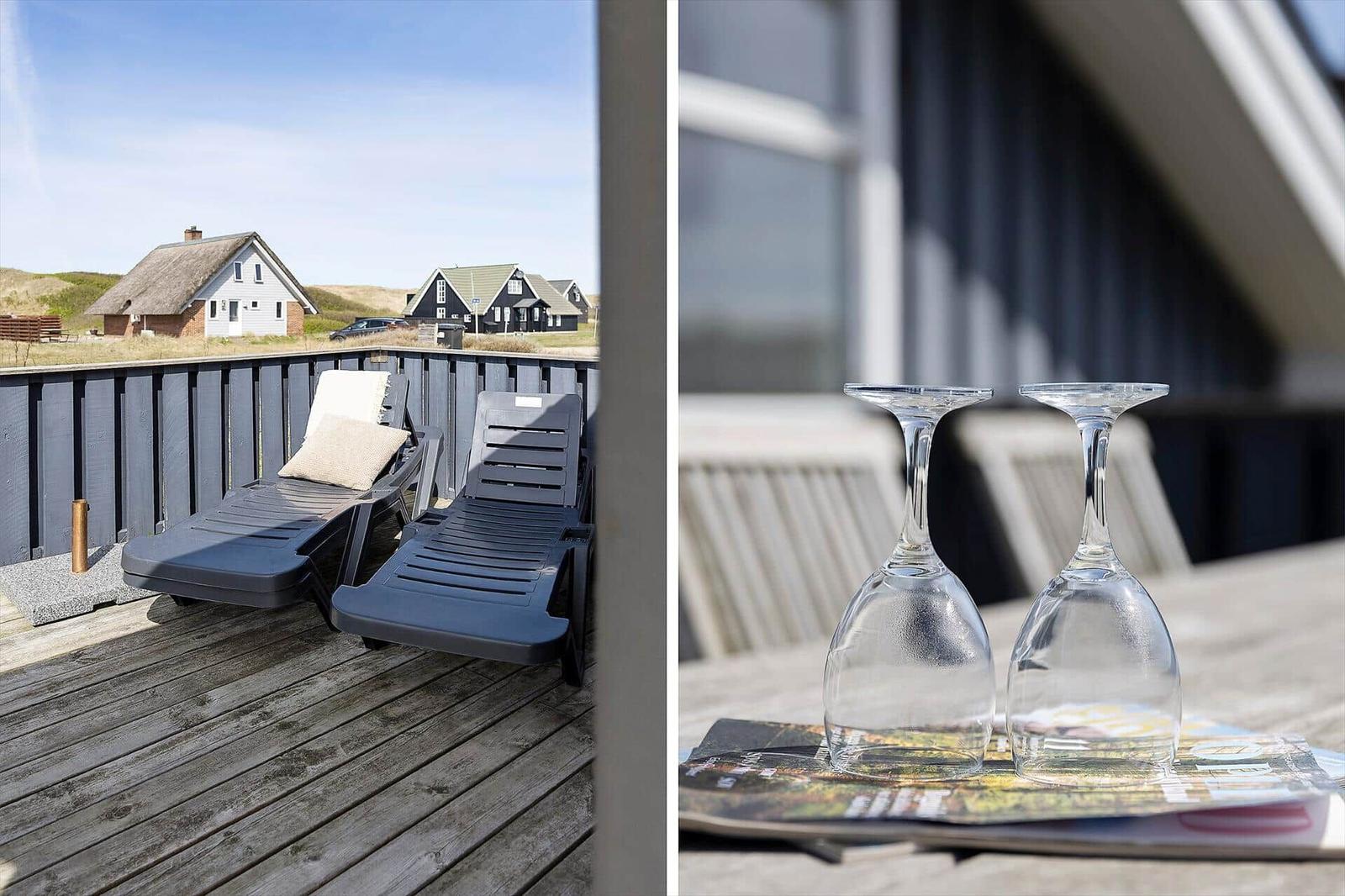 Terrasse mit Liegestühlen und Blick auf Häuser. Tisch mit zwei Weingläsern.