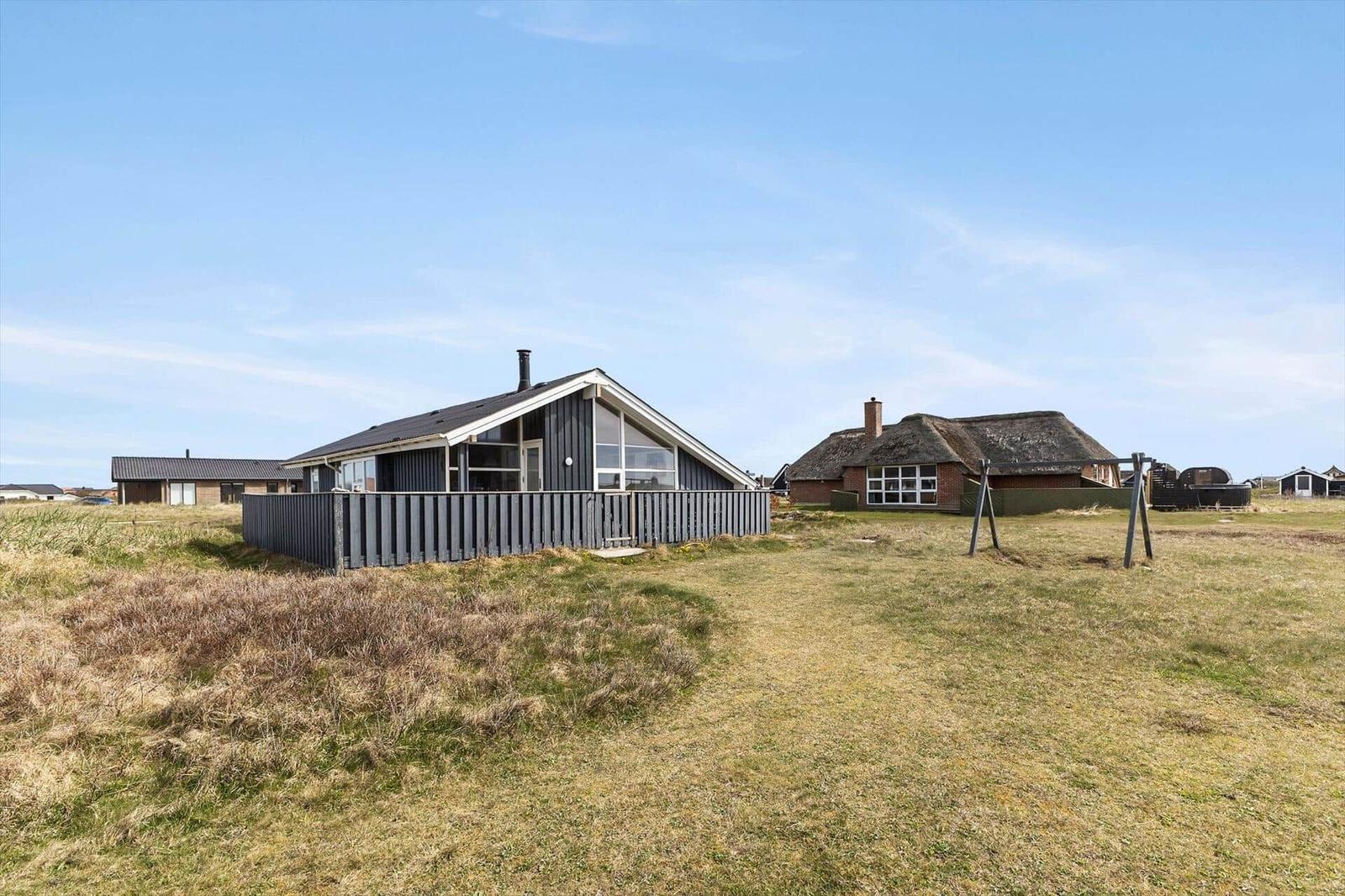 Moderne Villa mit Holzverkleidung und großen Fenstern auf grünem Grundstück.
