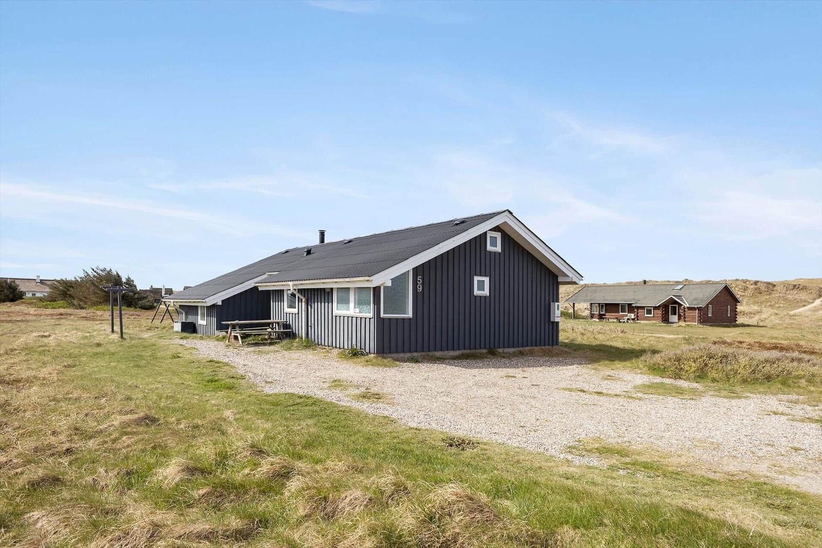 Ein dunkelblaues Ferienhaus mit Holzverkleidung und einem Gartenbereich.