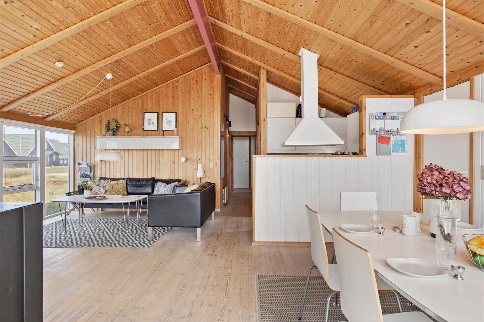 Wohn- und Essbereich mit Holzdecke, Sofa und Esstisch.
