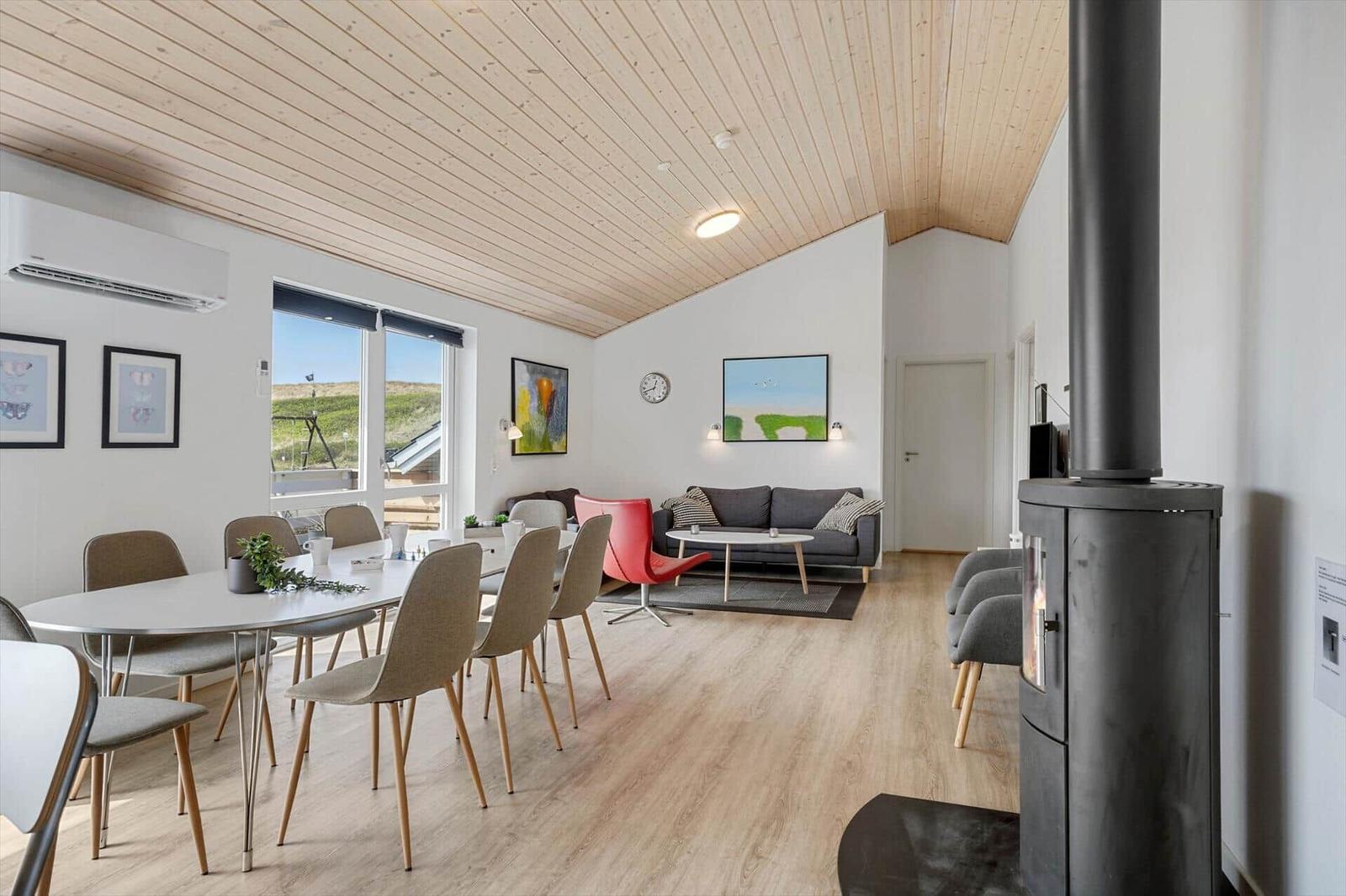 Wohn- und Essbereich mit Holzdecke, Esstisch, Sofa und Kaminofen.