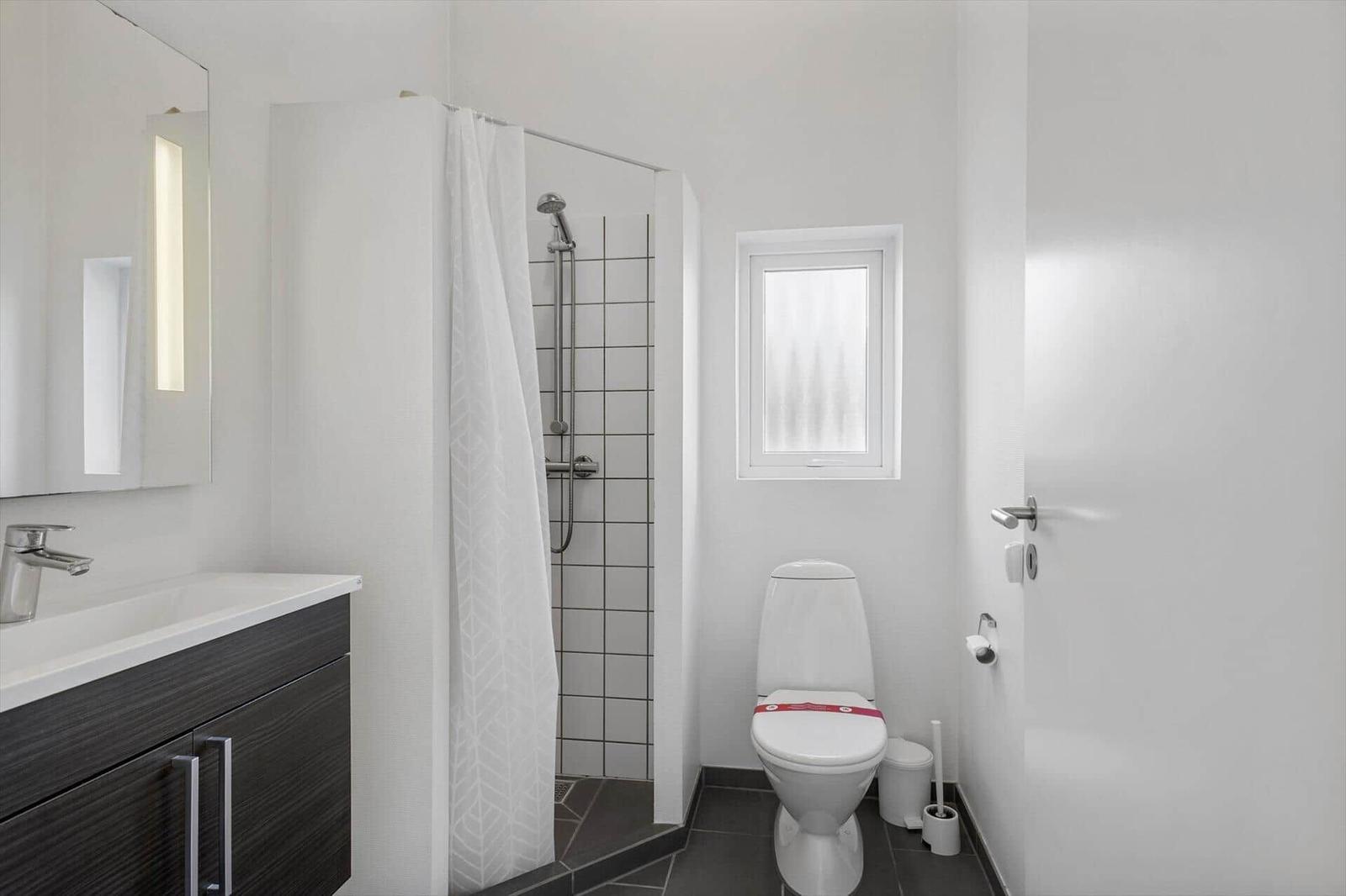 Badezimmer mit Dusche, Toilette und Waschbecken mit Spiegel