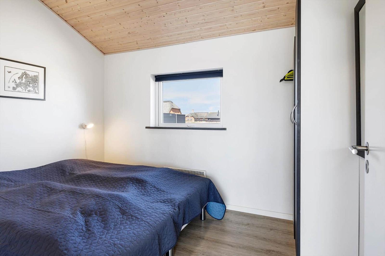 Schlafzimmer mit Bett, Fenster und Holzdecke.