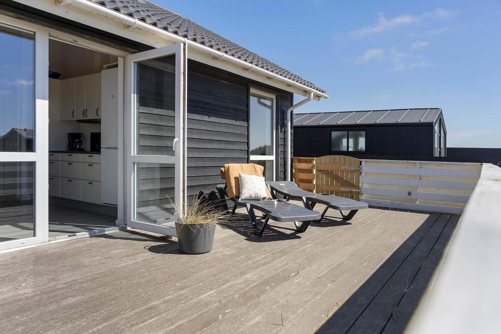Terrasse mit Liegestühlen und Blick ins Haus. Holzdeck und Schiebetür.