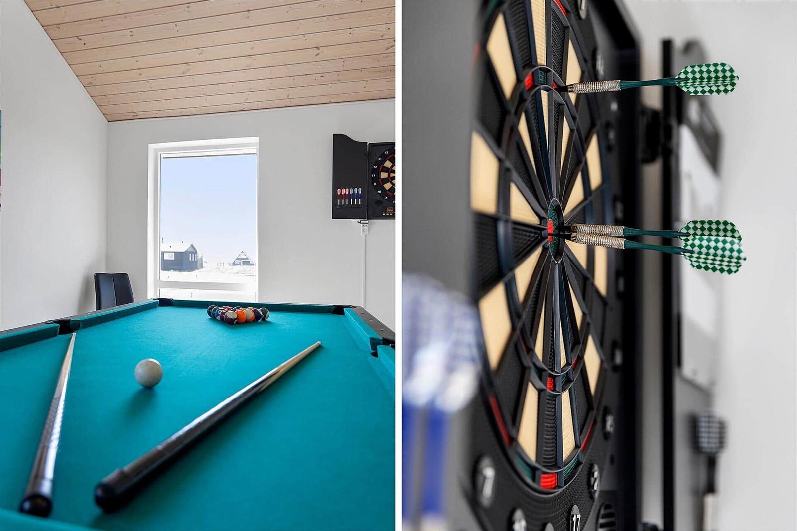 Billardtisch mit Kugeln und Queue. Dartboard mit Darts. Fensterblick auf schneebedeckte Landschaft.