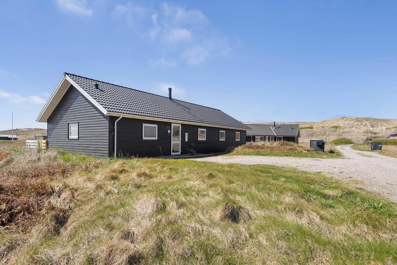 Ein modernes Haus mit grauem Holzschindeldach und weißen Fensterrahmen in einer grünen Landschaft.