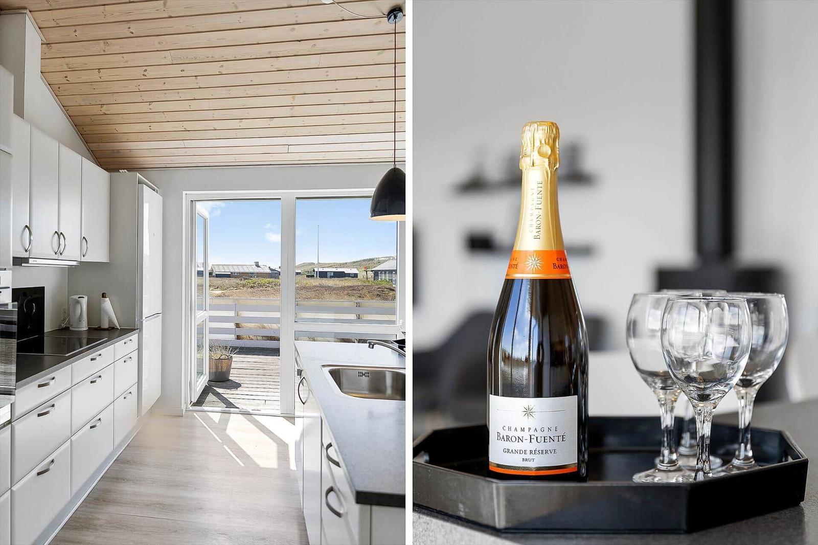 Küche mit Holzdecke und Blick auf Terrasse. Champagner und Gläser auf Servierplatte.