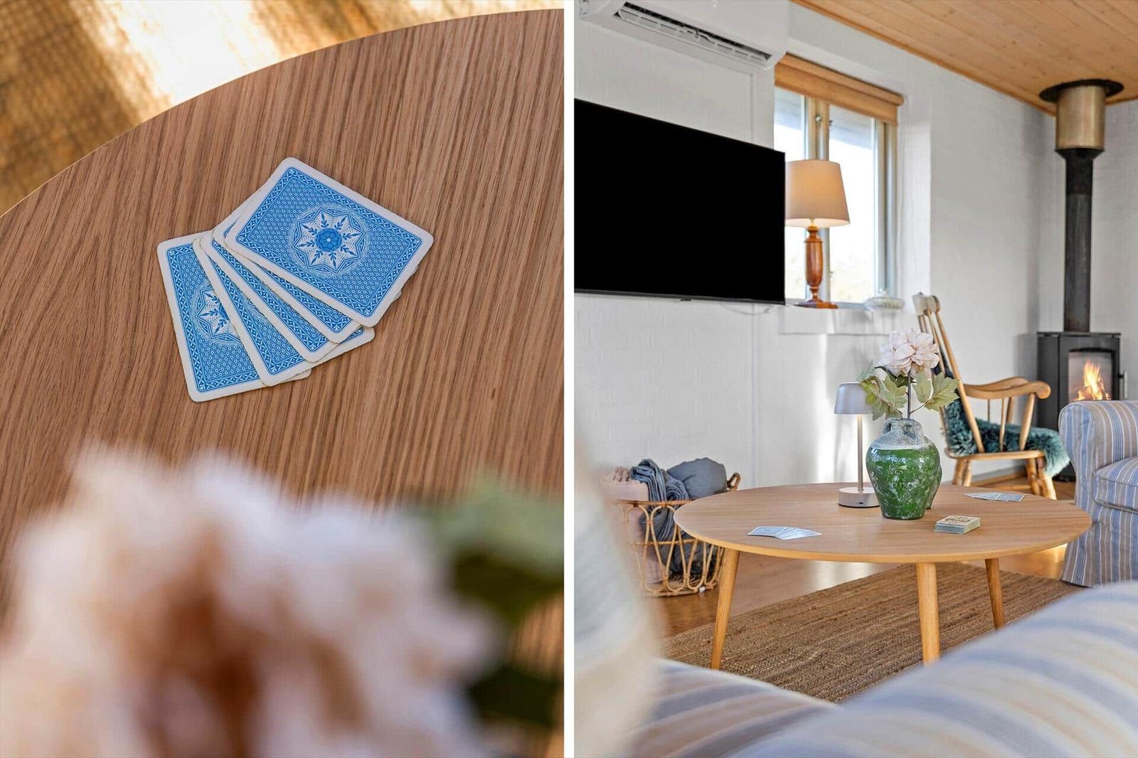 Holztisch mit Spielkarten und Wohnzimmer mit Kamin und Fernseher