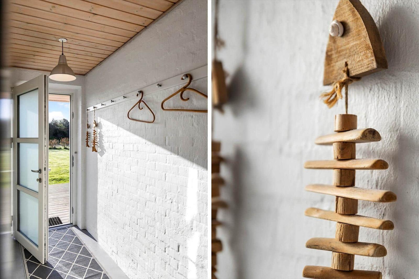 Eingangsbereich mit weißen Wänden, Holzdecke und Kleiderhaken. Holzdekoration an der Wand.