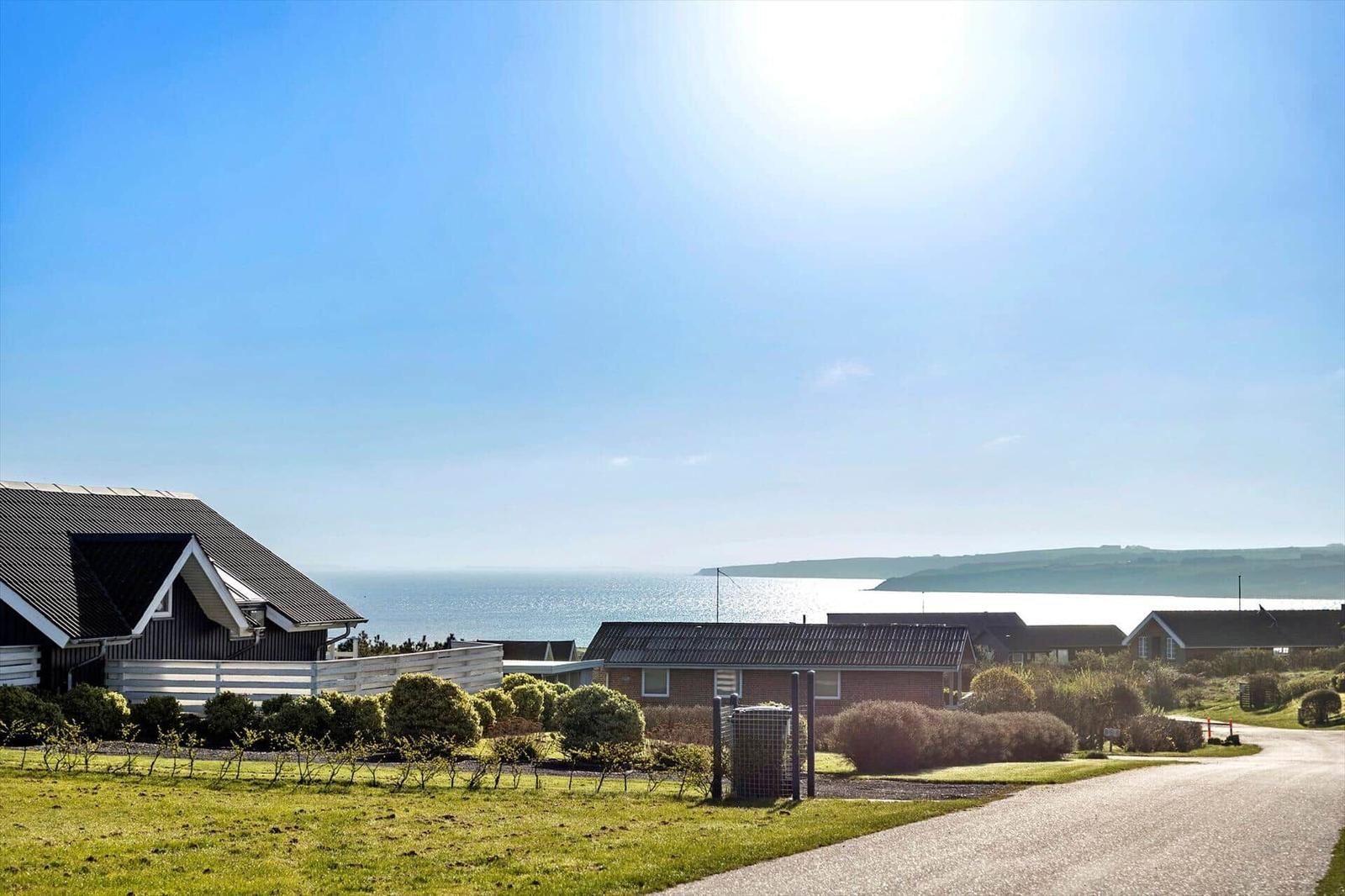 Haus mit Blick auf das Meer und grünen Garten unter blauem Himmel.
