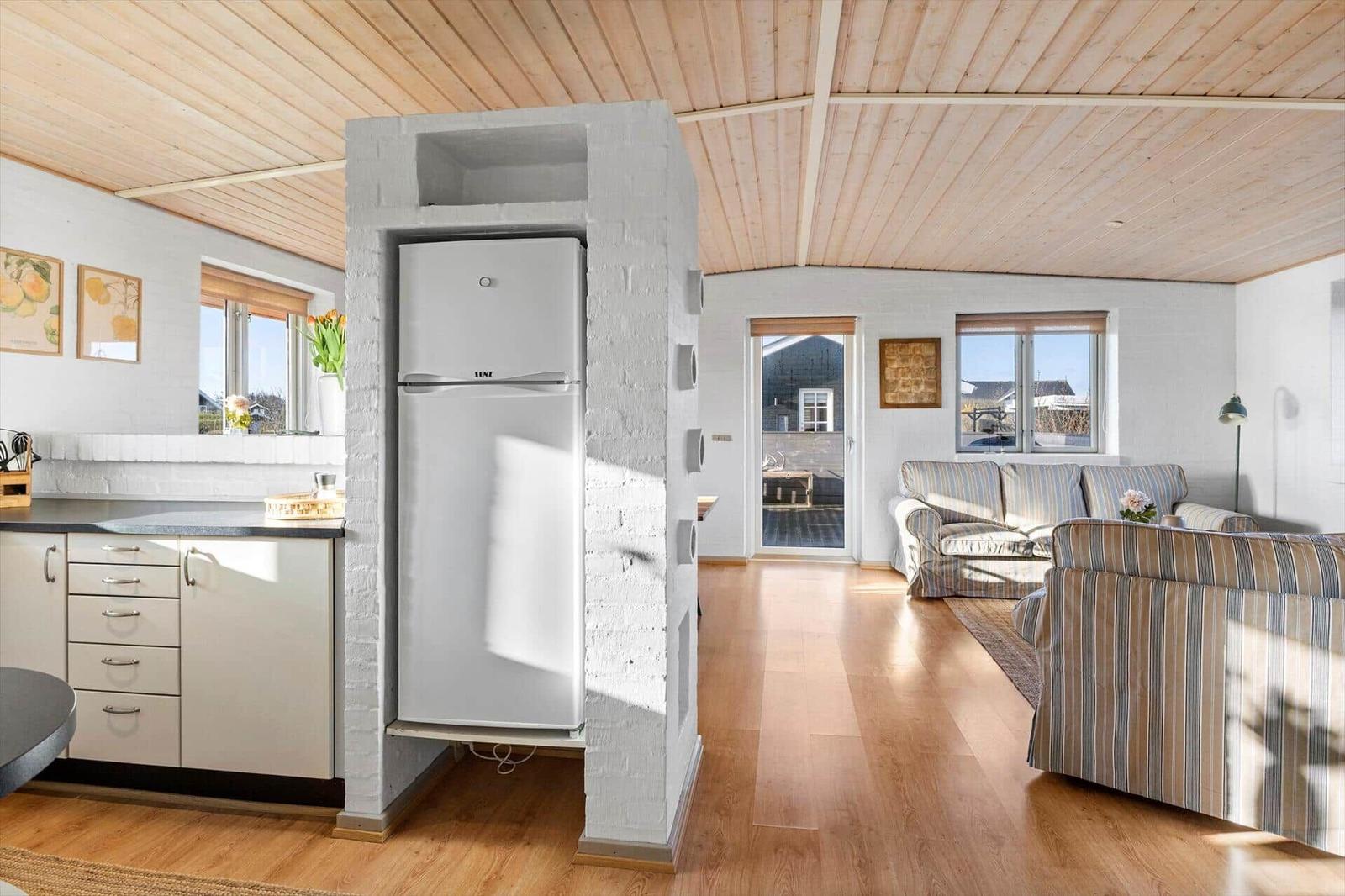 Küche mit Kühlschrank und Wohnbereich mit Sofa und Holzboden.