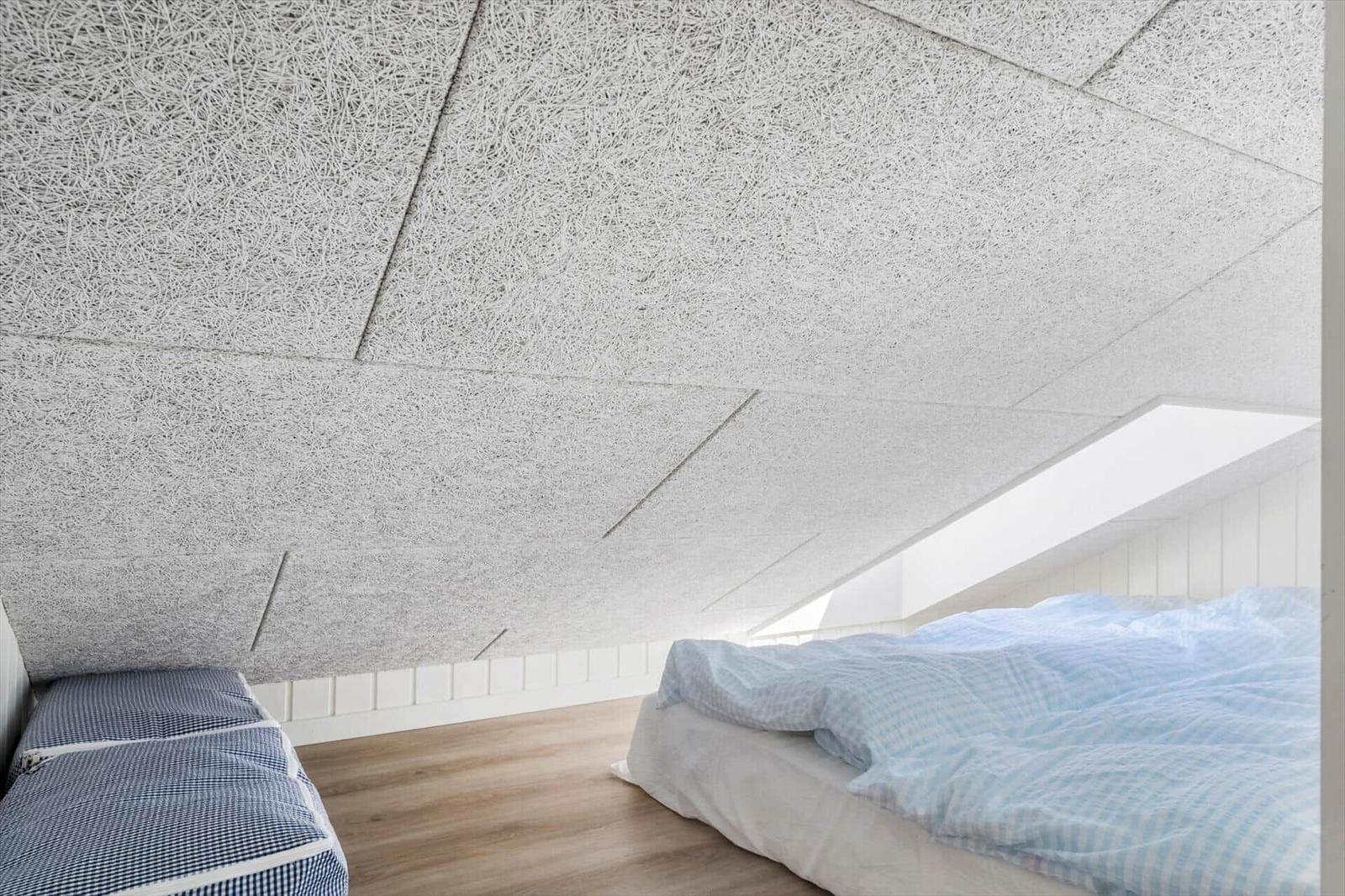 Schlafzimmer mit Dachschrägen, Dachfenster und blau-weißem Bettzeug.
