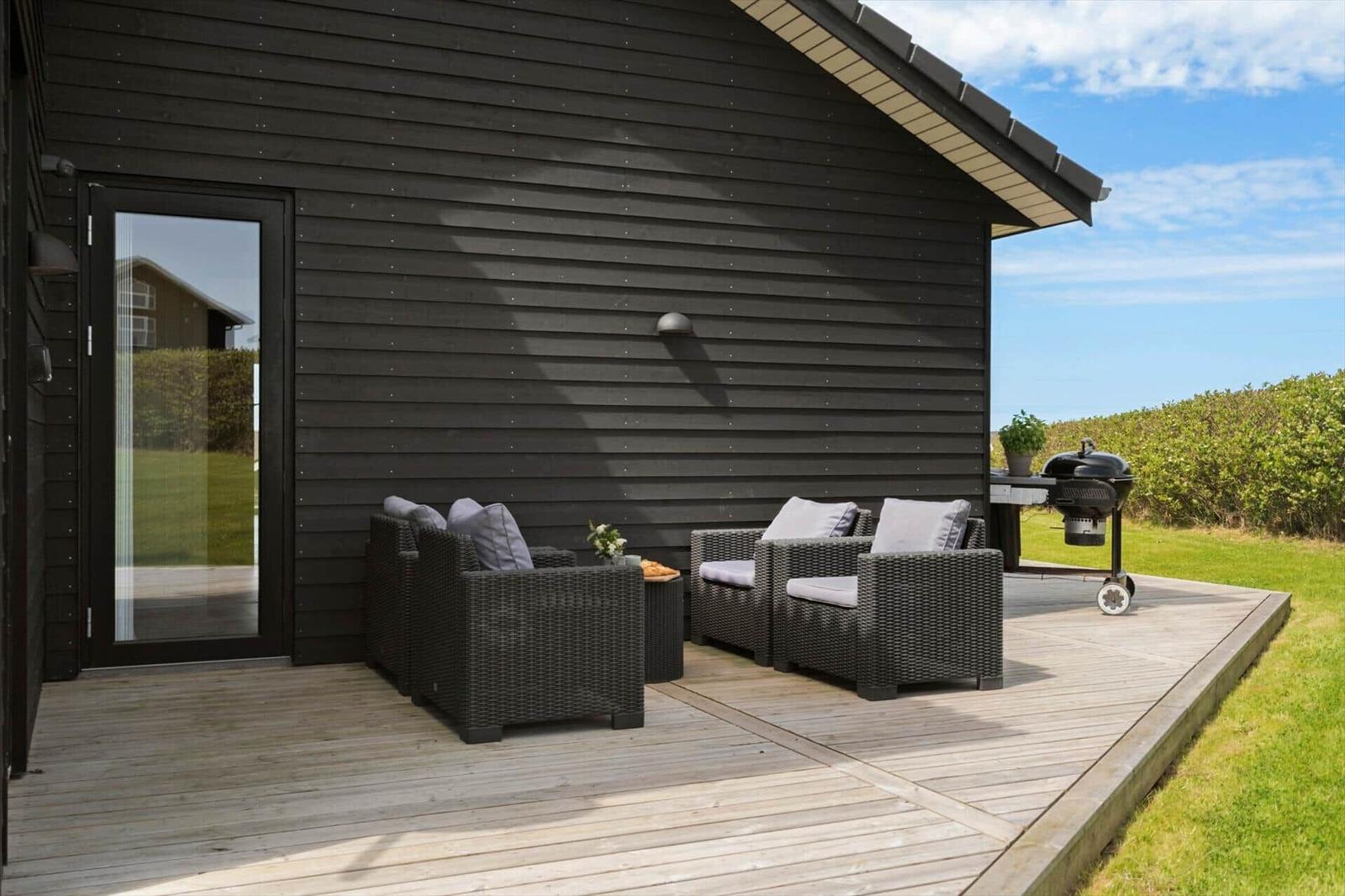 Terrasse mit Sitzgruppe, Grill und Glasfront zur Wohnung.