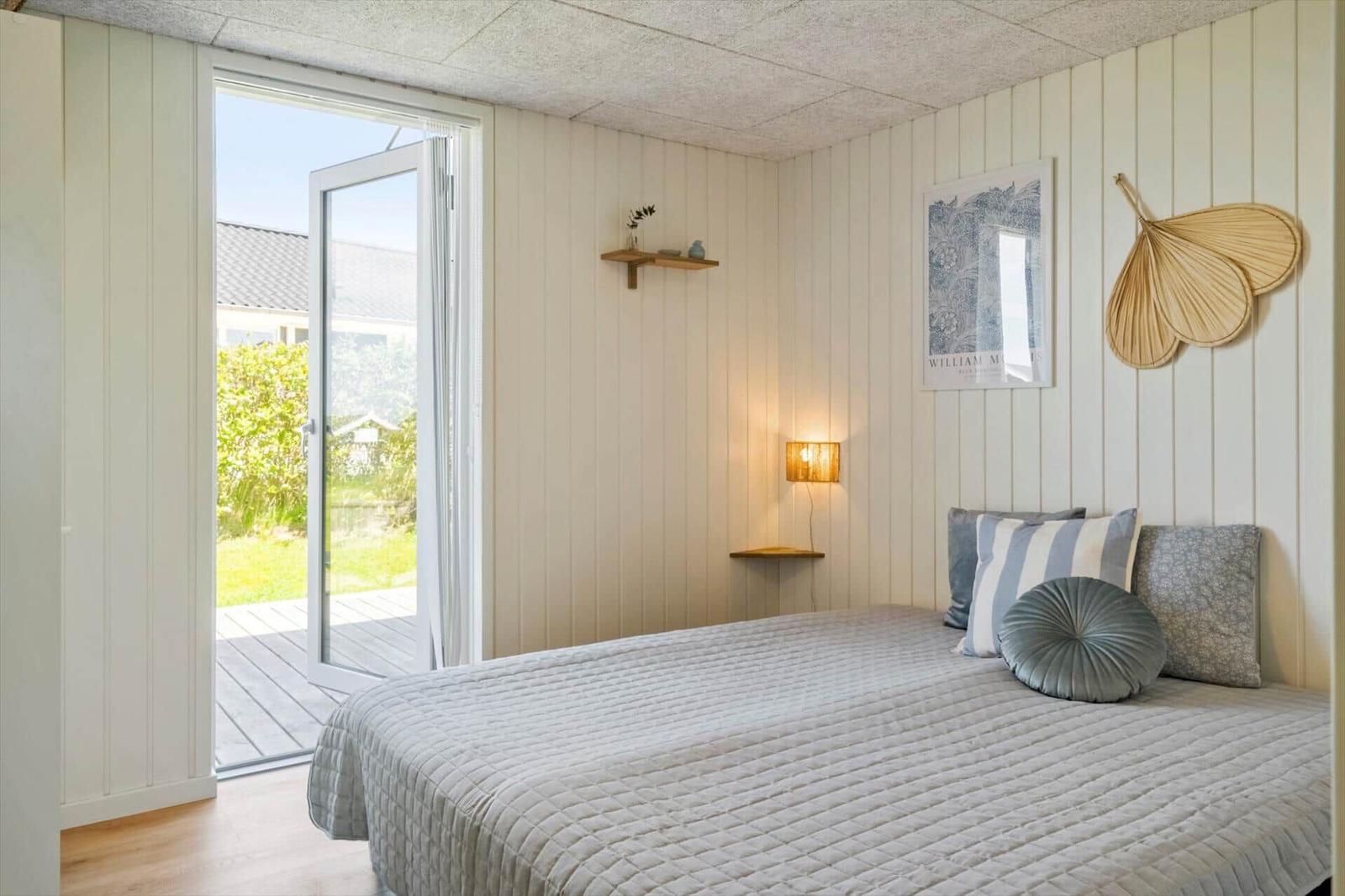 Schlafzimmer mit Bett, Wandbild und Tür zum Balkon.