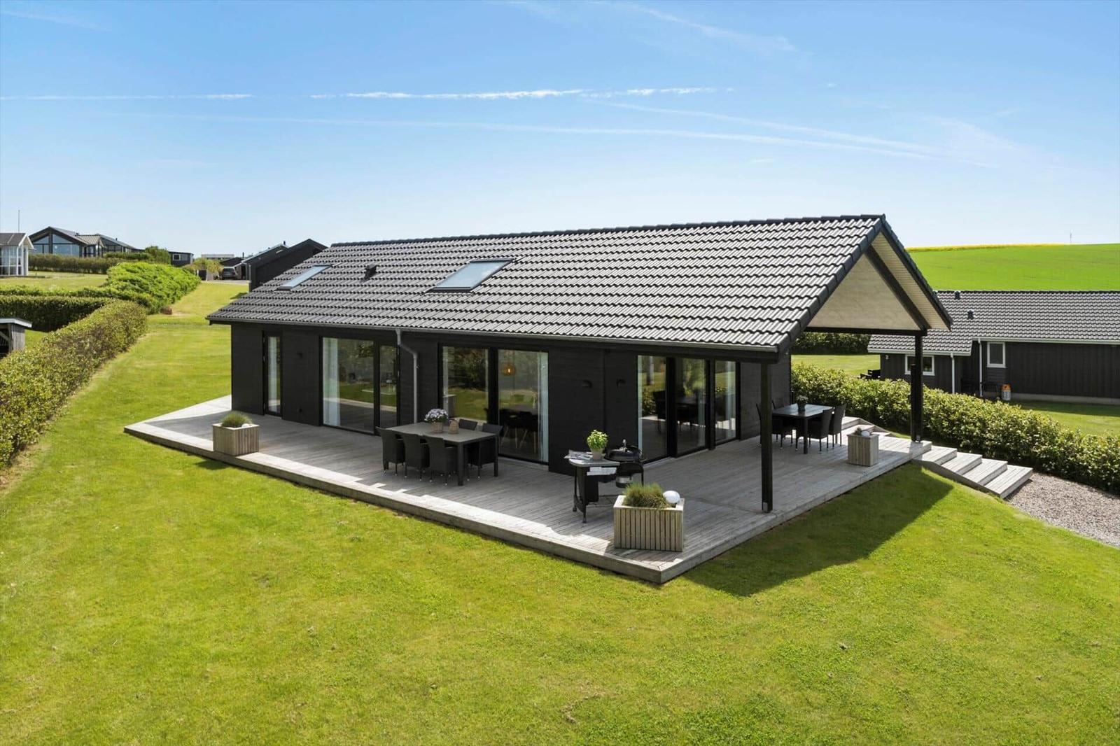 Moderne Villa mit großem Balkon, Terrasse und Garten. Sicht auf Felder und Himmel.
