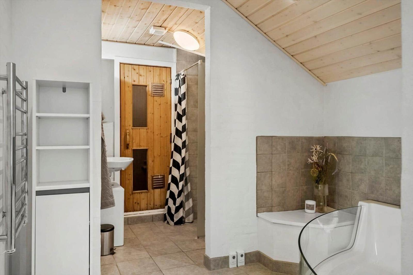 Badezimmer mit Dusche, Badewanne und Sauna.