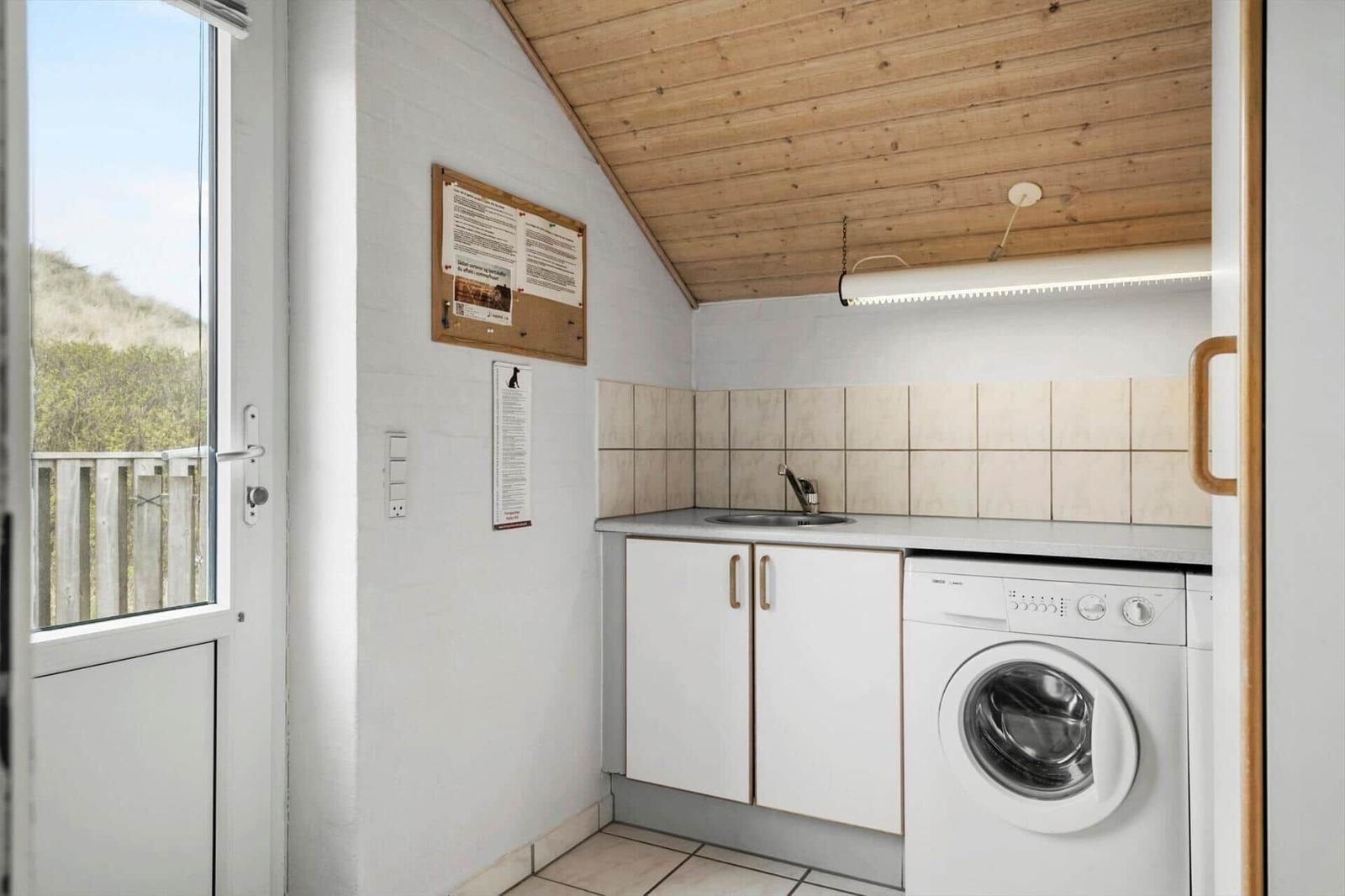Wohnung mit Waschmaschine, Spüle und Fenster zum Balkon.