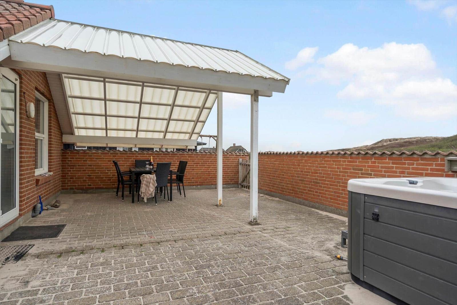Terrasse mit Pavillon, Sitzgruppe und Whirlpool. Blick auf den Himmel und eine Mauer.