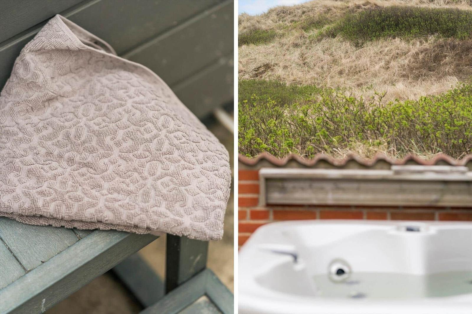 Gestrickte Handtuch auf Holzbank und Whirlpool mit Blick auf Dünen.