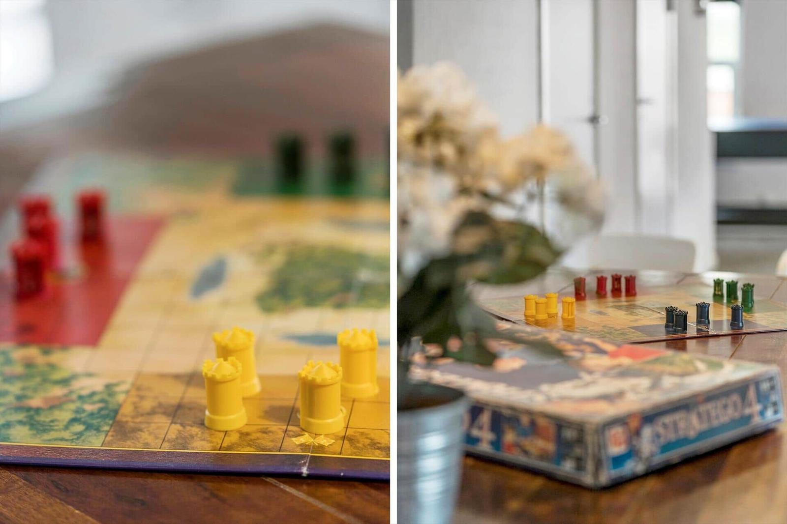 Spielbrett mit gelben und roten Türmen auf Holztisch. Spielbox und Blumen im Hintergrund.